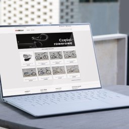 4K for Clients - Laptop wyświetla stronę internetową sklepu rowerowego z ofertą części i rowerów. Widoczny minimalistyczny design laptopa na tle jasnego otoczenia.