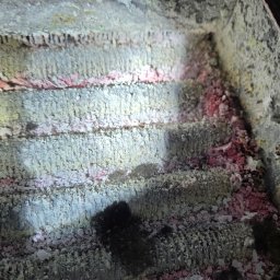 P.H.U. ARISTO - Zanieczyszczone wnętrze pieca gazowego z widocznymi osadami i korozją na elementach grzewczych. Niejednolita powierzchnia z różowymi i białymi nalotami.