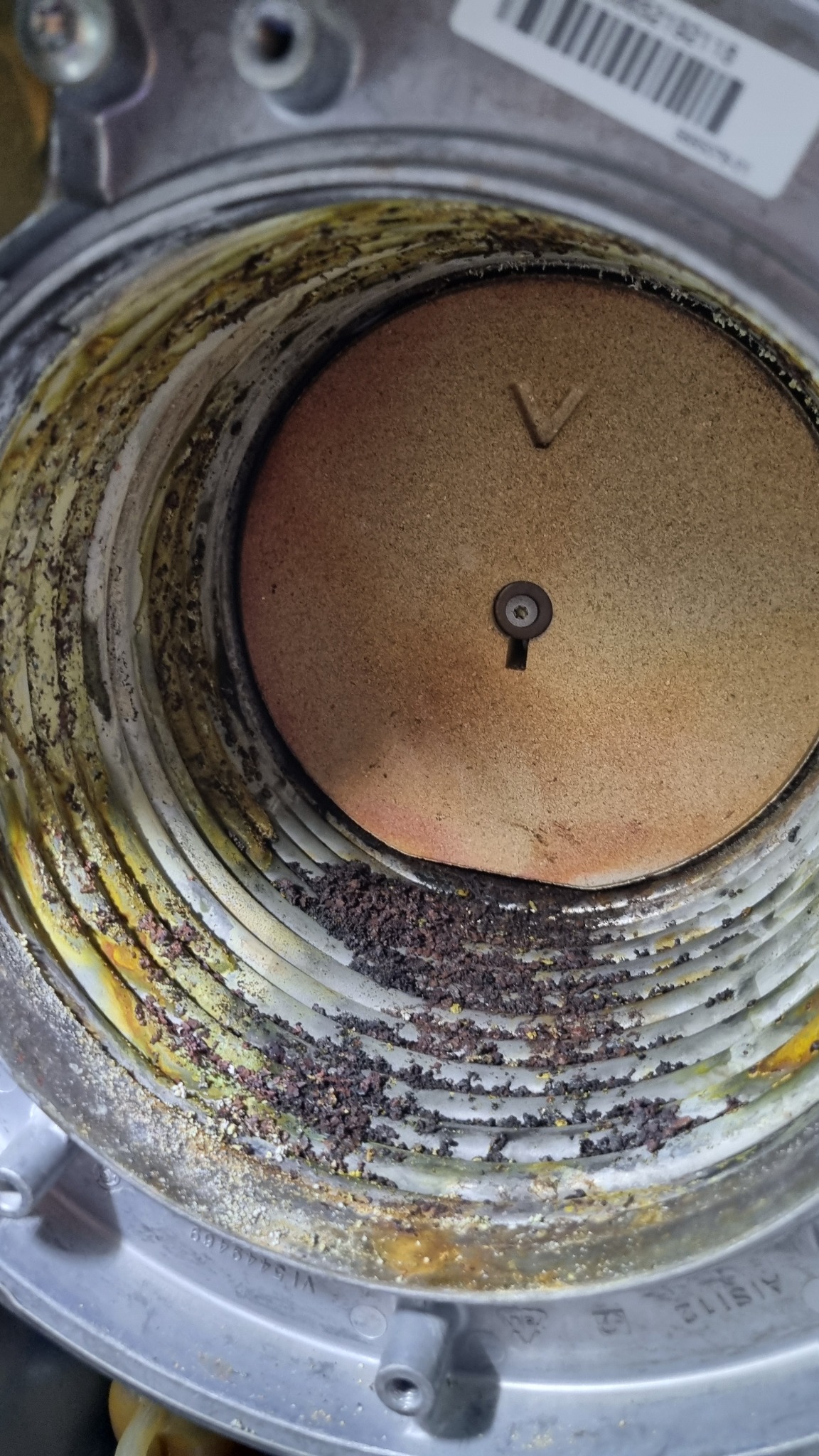 Zanieczyszczone wnętrze pieca gazowego z widocznymi osadami i korozją na elementach grzewczych. Detal z bliska ukazuje stopień zużycia i potrzebę serwisu.