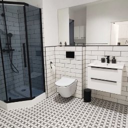 DOMINIK KAHL CRACOW LOCAL TOURS No.1 - Nowoczesna łazienka w bieli i czerni: kabina prysznicowa z czarną ramą, białe płytki, wzorzysta podłoga, umywalka z szafką i duże lustro.