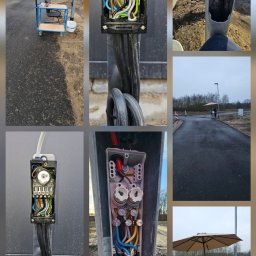 Elektro-Tech - Rozdzielnia elektryczna w słupie oświetleniowym na placu budowy, widoczne kable i bezpieczniki. Na zewnątrz stanowisko pracy pod parasolem.