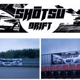 Michał Radwan - Baner reklamowy z grafiką samochodów driftowych na torze wyścigowym, zamontowany na barierkach i trybunach. Czarno-biała grafika z napisem 'Shotsu Drift'.