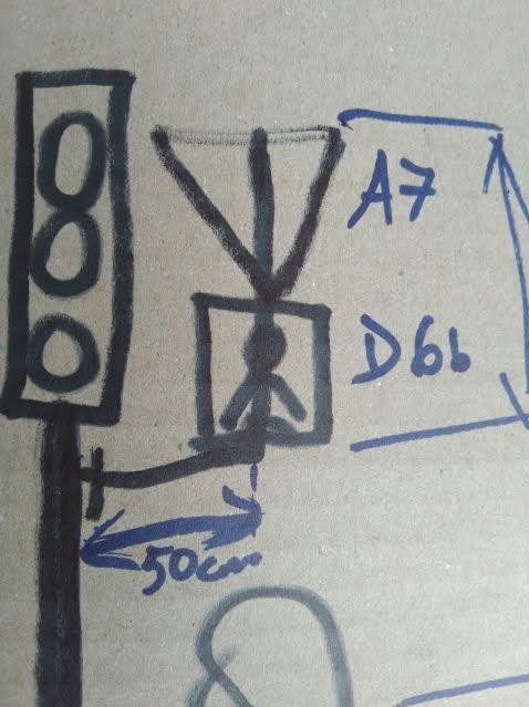 Szkic sygnalizacji świetlnej i znaku drogowego z oznaczeniami 'A7' i 'D6b' oraz wymiarem 50cm, wykonany niebieskim markerem na szarym tle.