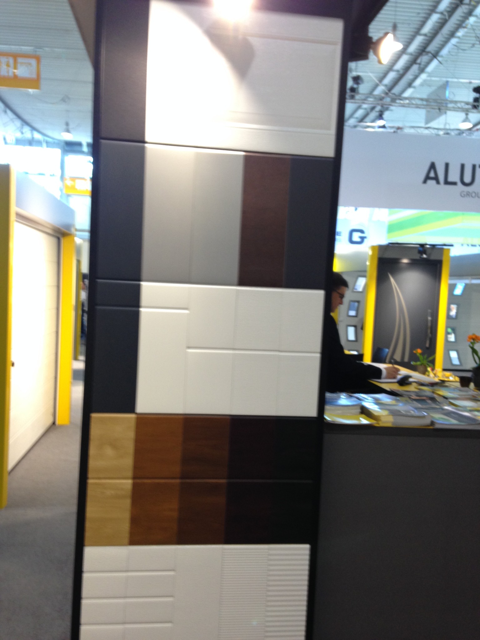 Ekspozycja paneli drzwiowych w Katowicach: różne kolory i faktury, od białych po drewnopodobne, prezentowane na czarnym stelażu. Widoczny fragment stoiska targowego.