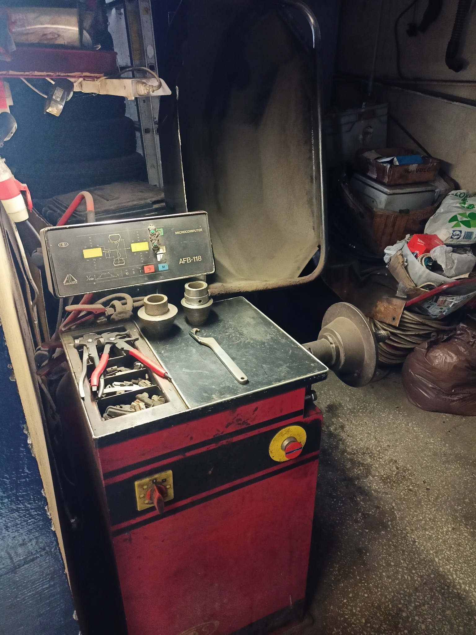 Wyważarka do kół AFB-118 z narzędziami i elementami mocującymi, ustawiona w warsztacie. Widoczne detale urządzenia i otoczenie robocze.