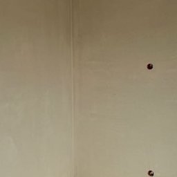 SPEED - PUB RADOSŁAW BUCHALIK - Wnętrze po tynkowaniu maszynowym: gładkie, beżowe ściany, surowy betonowy sufit i podłoga. Widoczne dwa otwory na gniazdka elektryczne.