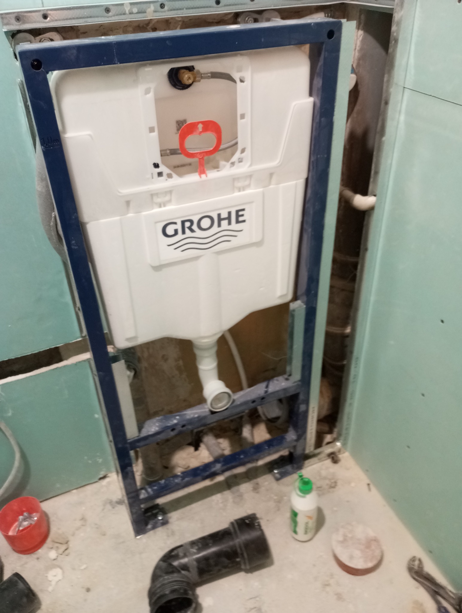 Stelaż podtynkowy Grohe zamontowany w łazience, widoczne elementy instalacji i narzędzia. Etap prac wykończeniowych, przed zabudową.