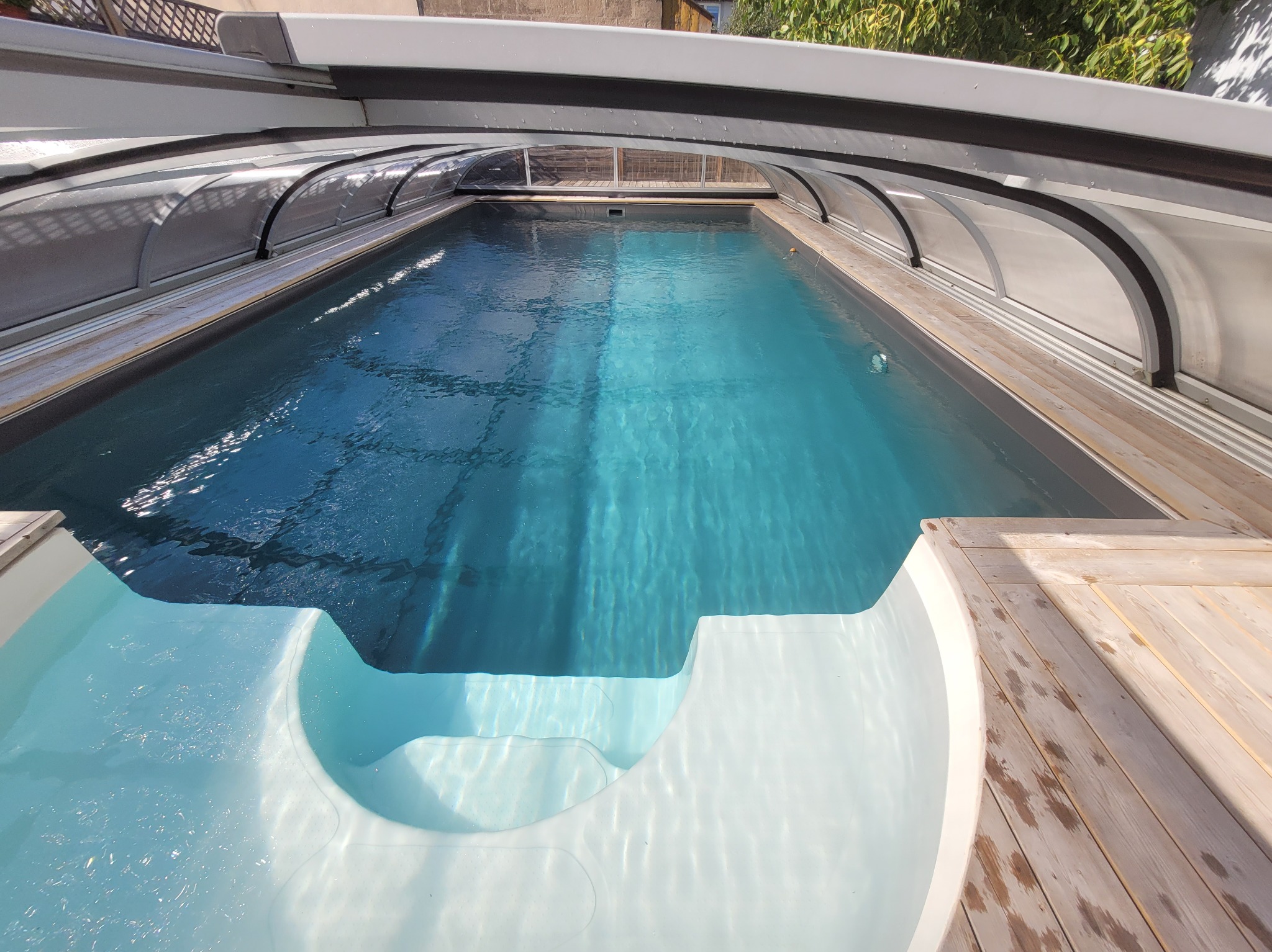 Basen poliestrowy w zabudowie z deski drewnianej, niskie zadaszenie