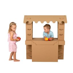 SARA STUDIO - Dzieci bawią się w sklep w tekturowym straganie. Dziewczynka z jabłkiem, chłopiec za ladą z pomarańczą i pomidorem. Jasne tło, neutralne oświetlenie.