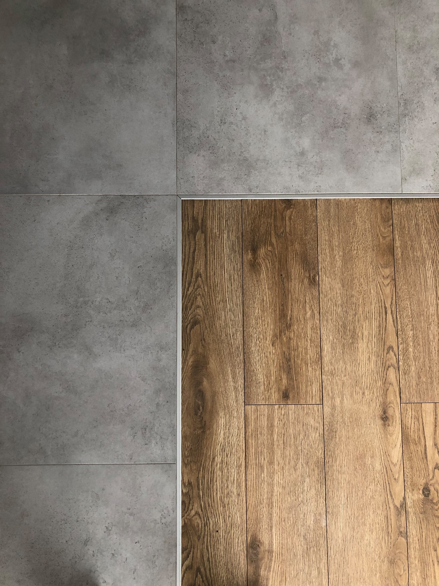 Połączenie płytek imitujących beton i paneli drewnopodobnych listwą w kolorze aluminium. Realizacja we Wrocławiu. Nowoczesne wykończenie podłogi.