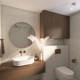 Zinna Interiors - Nowoczesna łazienka z owalną umywalką, okrągłym lustrem i drewnianymi szafkami. Beżowe płytki, złote akcenty i dekoracyjne trawy pampasowe dodają elegancji.
