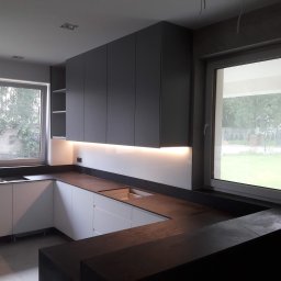 TOMASZEWSKI MEBLE PAWEŁ TOMASZEWSKI - Nowoczesna kuchnia w kształcie litery L z szarymi szafkami wiszącymi i białymi dolnymi, oświetlona listwą LED pod szafkami, z ciemnym blatem.