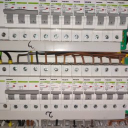 Rozdzielnica elektryczna z zainstalowanymi bezpiecznikami Noark Ex9BN B16 i C16, widoczne przewody. Ujęcie z bliska, ukazujące detale instalacji.