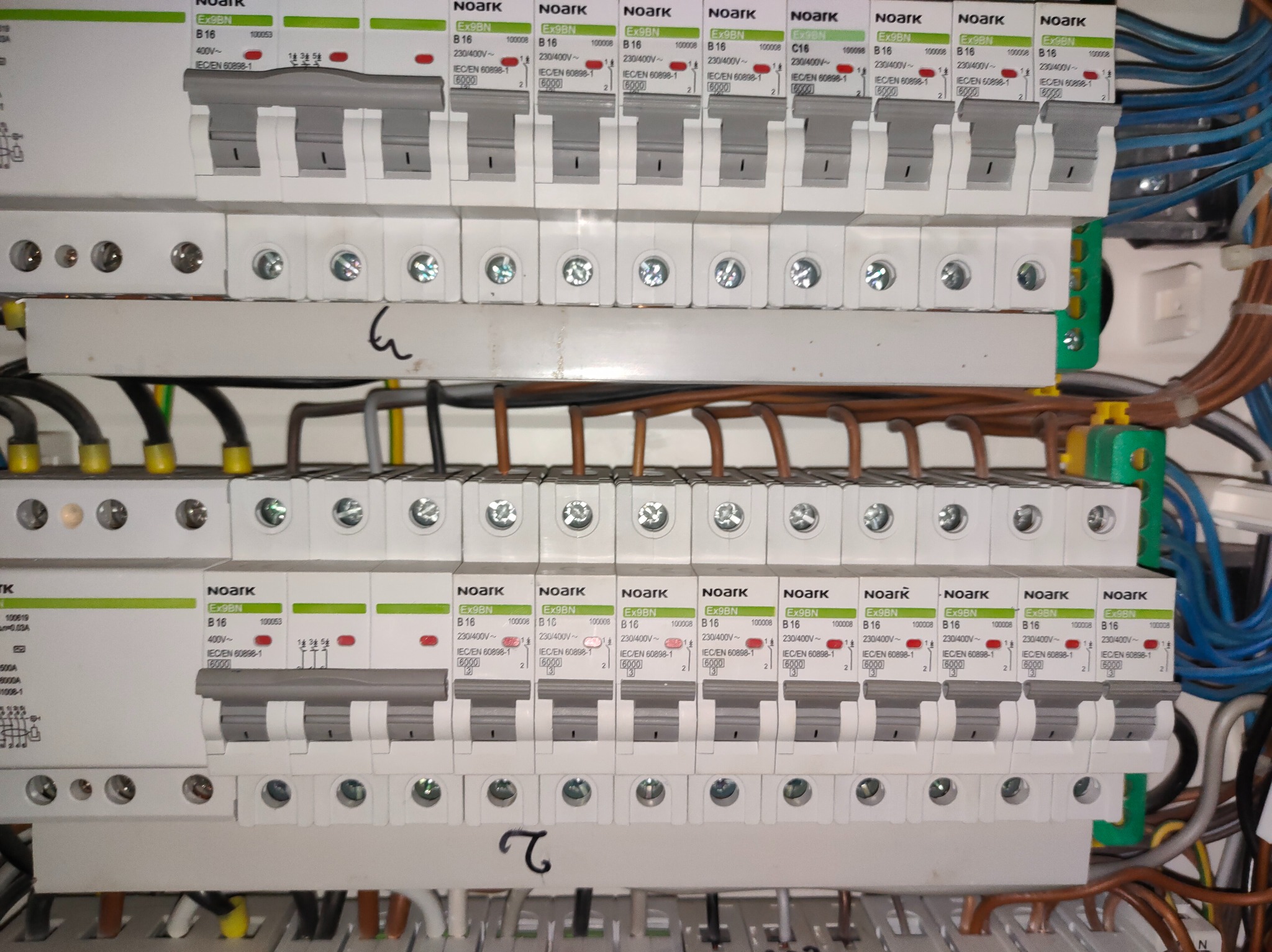 Rozdzielnica elektryczna z zainstalowanymi bezpiecznikami Noark Ex9BN B16 i C16, widoczne przewody. Ujęcie z bliska, ukazujące detale instalacji.
