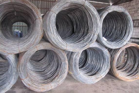 Zestaw zwiniętych zwojów drutu wiązałkowego na szarym podłożu. Drut w szpulach, zabezpieczony sznurkiem, ułożony jeden na drugim. Widoczne zróżnicowanie odcieni szarości.