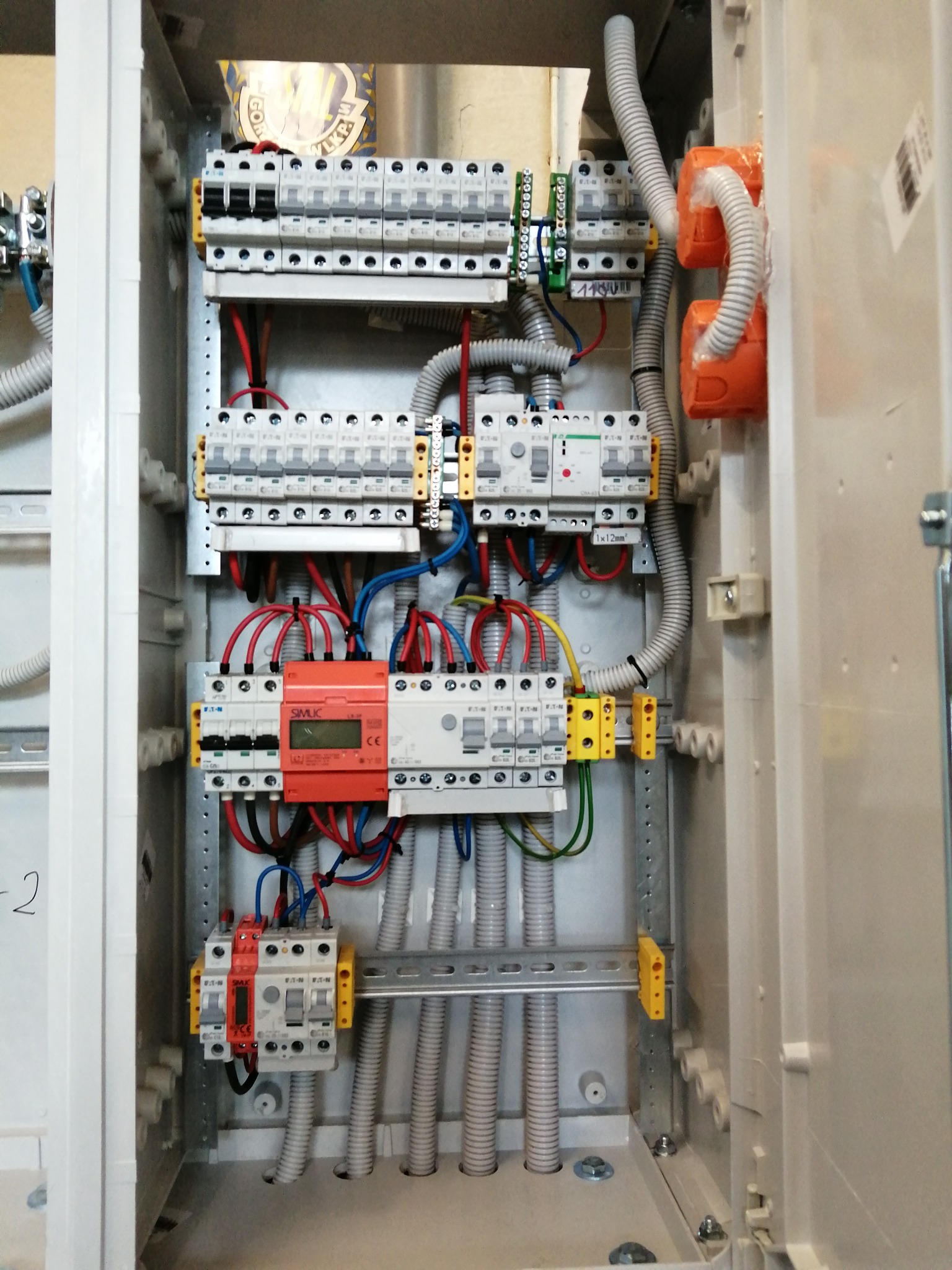 Rozdzielnia elektryczna wewnątrz szafy, widoczne zabezpieczenia, przewody i elementy montażowe. Instalacja wykonana schludnie, z dbałością o detale.