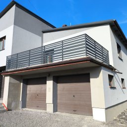 A.I.M Weld Usługi Spawalnicze MARIUSZ PARUZEL - Nowoczesna balustrada balkonowa z poziomych profili na tle dwukondygnacyjnego domu z garażem i błękitnym niebem. Minimalistyczny design, jasna kolorystyka.