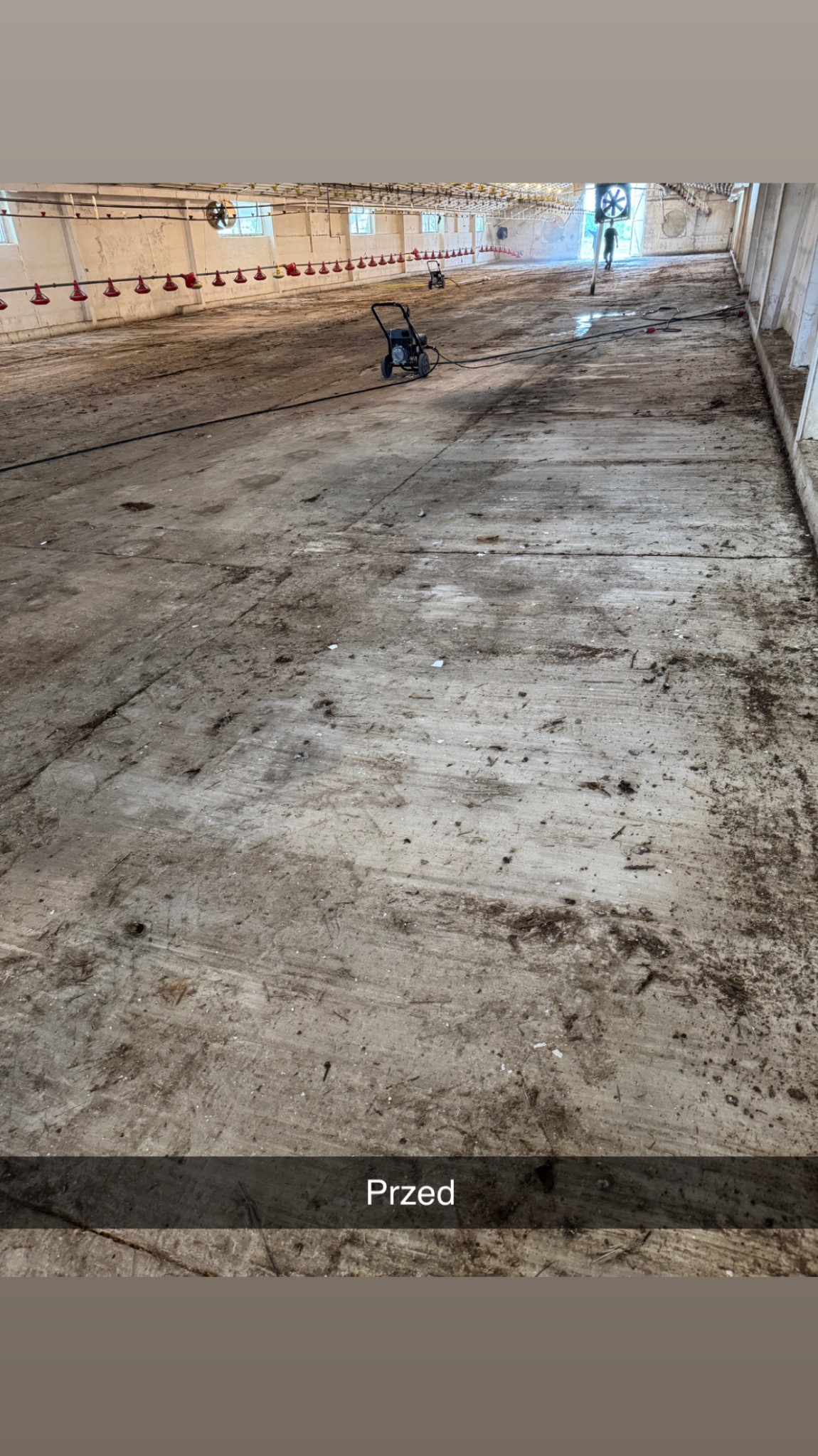 Wnętrze hali przed czyszczeniem. Widoczna brudna posadzka betonowa i myjki ciśnieniowe w tle. Ujęcie z perspektywy podłogi, z napisem 'Przed' na dole.