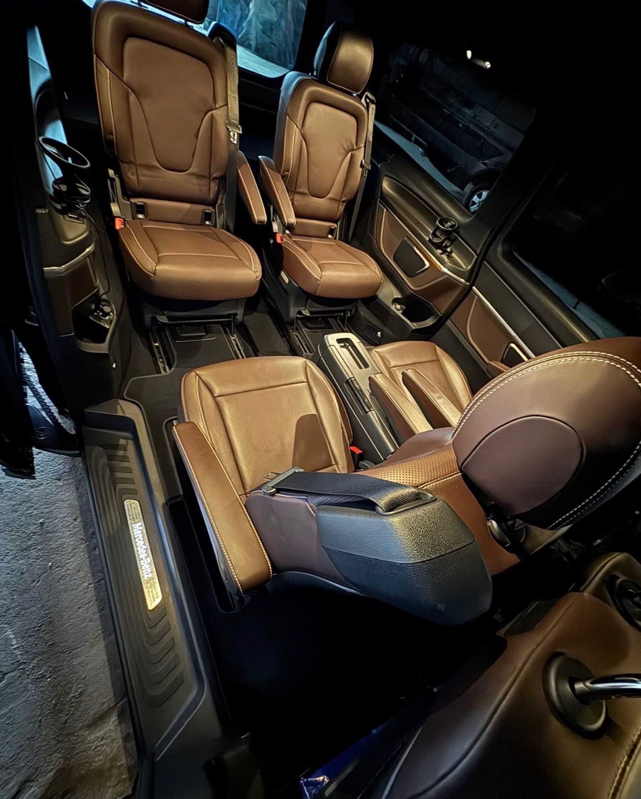 Luksusowe wnętrze busa Mercedes-Benz z brązowymi skórzanymi fotelami, widok z perspektywy pasażera, podkreślający komfort i przestrzeń. Detale wykończenia.