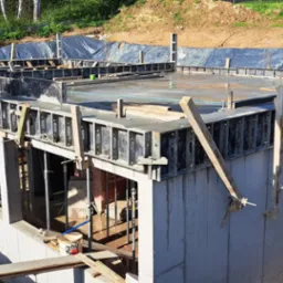 Wylane fundamenty z szalunkami i zbrojeniami, widoczne ślady po zalewaniu betonem, przygotowane do dalszej budowy domu.