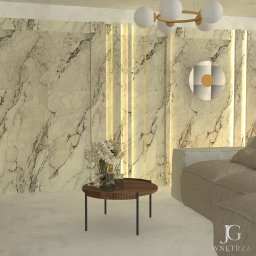 JGwnętrza - Elegancki salon z marmurową ścianą, oświetleniem LED, okrągłym stolikiem z kwiatami i beżową sofą. Nowoczesny design wnętrza z dekoracyjnym oświetleniem.