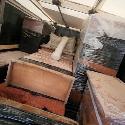 WenaBud - Meble i przedmioty zabezpieczone folią i wewnątrz skrzyni ładunkowej, gotowe do transportu. Widoczne drewniane elementy i białe poduszki.