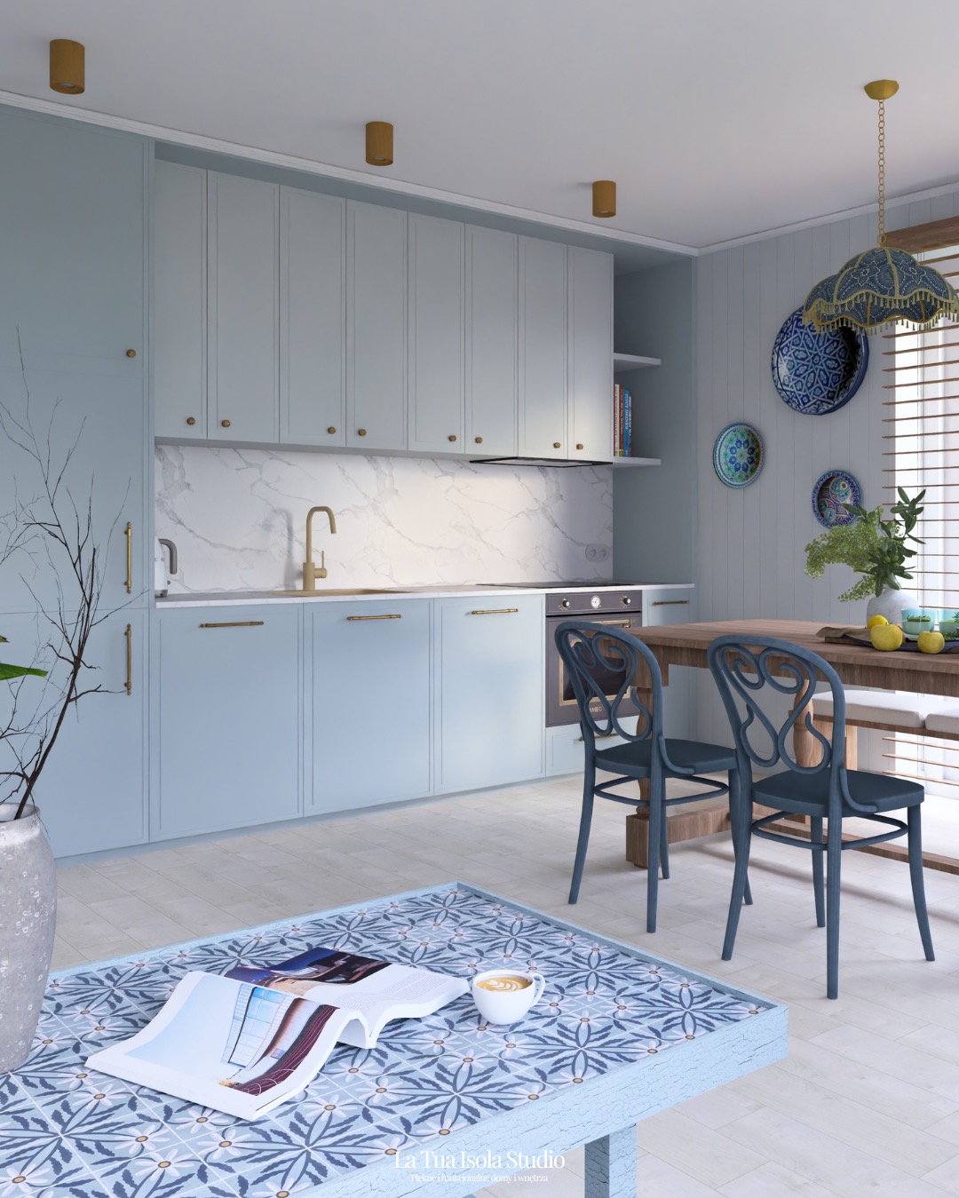 Jasna kuchnia w stylu śródziemnomorskim z błękitnymi szafkami, marmurowym blatem i drewnianym stołem. Na pierwszym planie stolik kawowy z wzorem i filiżanka.
