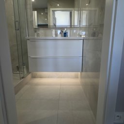 Fast Bilding Vasyl Voloshyn - Nowoczesna łazienka z podświetlaną szafką pod umywalką, kabiną prysznicową i lustrem. Jasne płytki podłogowe i marmurowe wykończenie ścian.