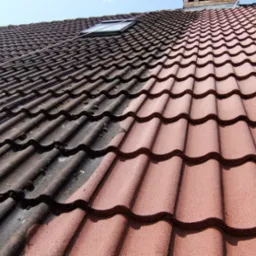 Częściowo wyczyszczony dach z dachówki ceramicznej, widoczna wyraźna różnica między brudną, porośniętą mchem lewą stroną a czystą, czerwoną prawą stroną dachu.