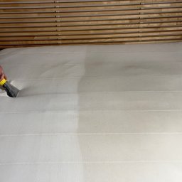 SmartCleaning - Czyszczenie materaca metodą ekstrakcyjną, widoczna różnica w czystości po lewej stronie, drewniane wezgłowie łóżka w tle.