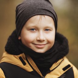 Studio Kadr Łukasz Michalik - Portret uśmiechniętego chłopca o niebieskich oczach w czapce i kurtce 4F na rozmytym tle. Ujęcie z bliska, naturalne światło.