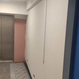 Oleksandr Soboda - Wnętrze w trakcie prac wykończeniowych: ściana z zamontowanymi gniazdkami elektrycznymi, fragment ściany z płyt karton-gips, zabezpieczona podłoga i widoczny fragment windy.