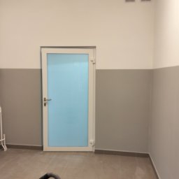 Oleksandr Soboda - Wnętrze po remoncie: biało-szare ściany z nowymi drzwiami z niebieską szybą. Na podłodze płytki, w rogu widoczny odkurzacz przemysłowy.