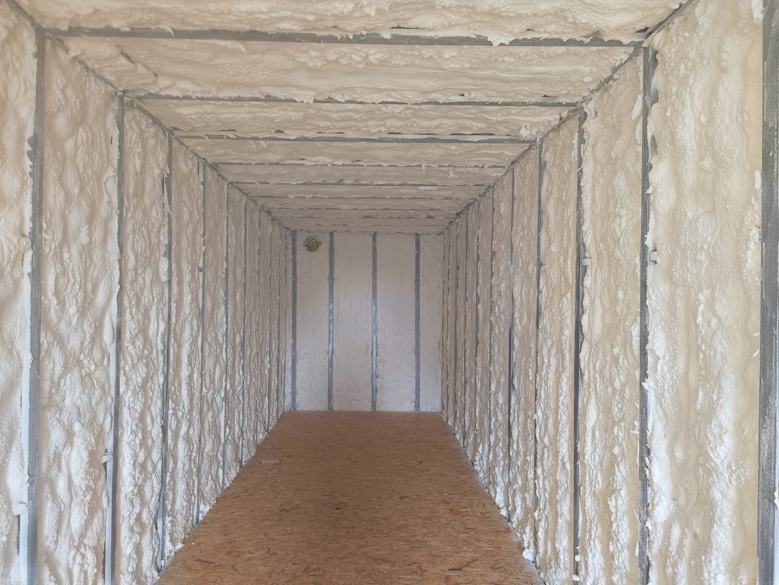 Wnętrze kontenera po natrysku pianki PUR na ściany i sufit, widoczne metalowe profile konstrukcyjne. Podłoga z płyty OSB.