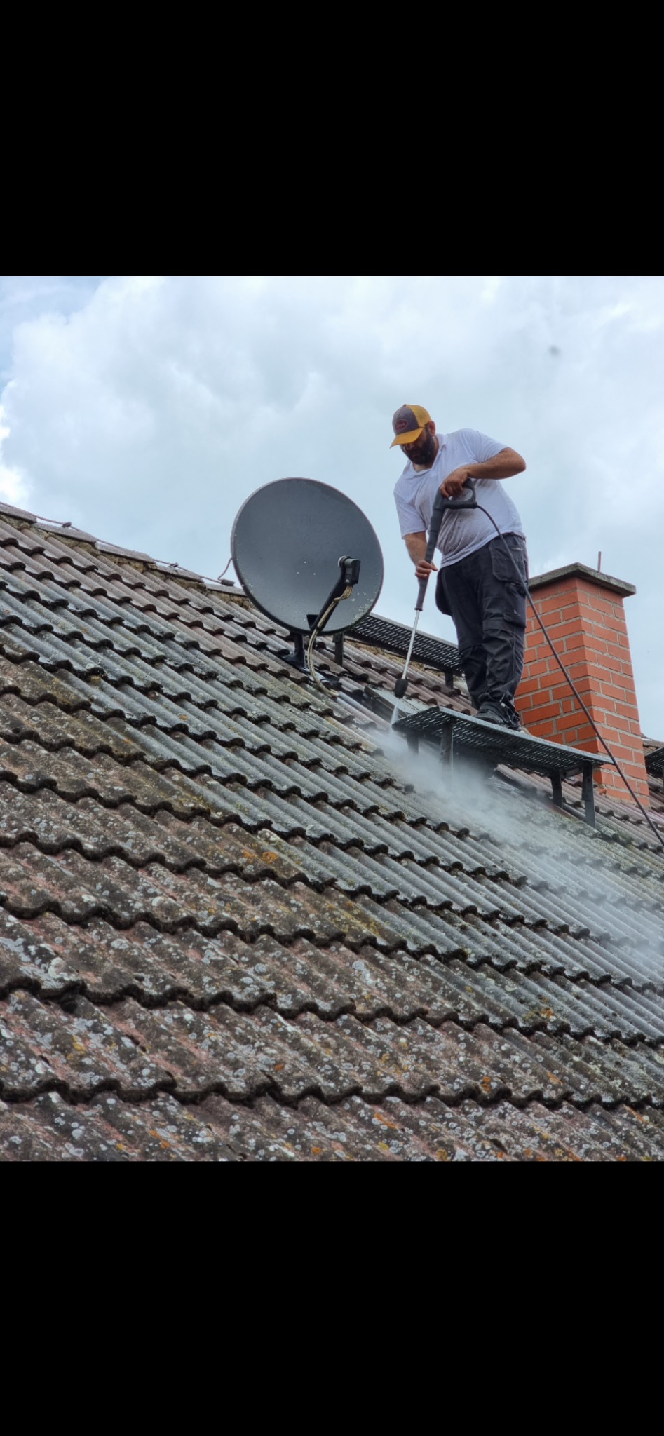 Czyszczenie dachówki ciśnieniowo z rusztowania. Widoczna antena satelitarna i komin. Praca na wysokościach.