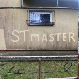 ST MASTER Anatolii Pavlenko i Oleksandr Sliuzka spółka cywilna - Elewacja budynku z częściowo usuniętym brudem, widoczne rusztowanie i okno z ozdobną kratą. Napis 'ST MASTER' wyczyszczony na ścianie.