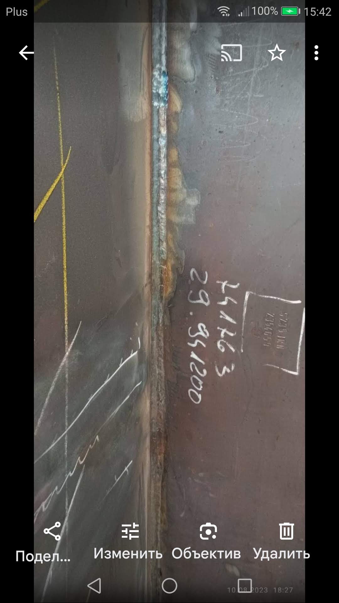 Spoina spawalnicza na metalowej powierzchni z naniesionymi oznaczeniami technicznymi. Widoczne ślady po spawaniu i żółte linie pomocnicze.