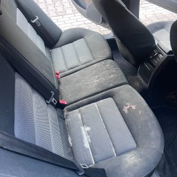 NCLEAN - mobilne pranie tapicerki - Zabrudzona, szara tapicerka tylnych siedzeń samochodowych z widocznymi plamami i zanieczyszczeniami, wymagająca profesjonalnego prania i czyszczenia.