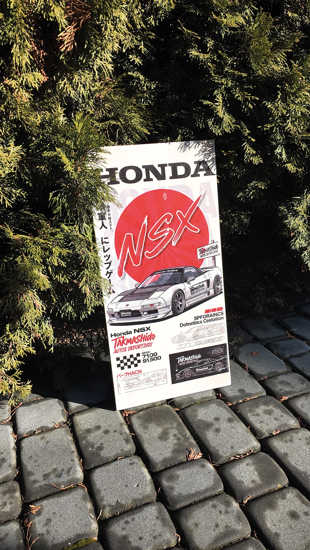 Plakat Honda NSX Takmashido Autos Deportivos, oparty o kostkę brukową i otoczony zielonymi gałązkami, prezentuje grafikę auta i japońskie napisy.