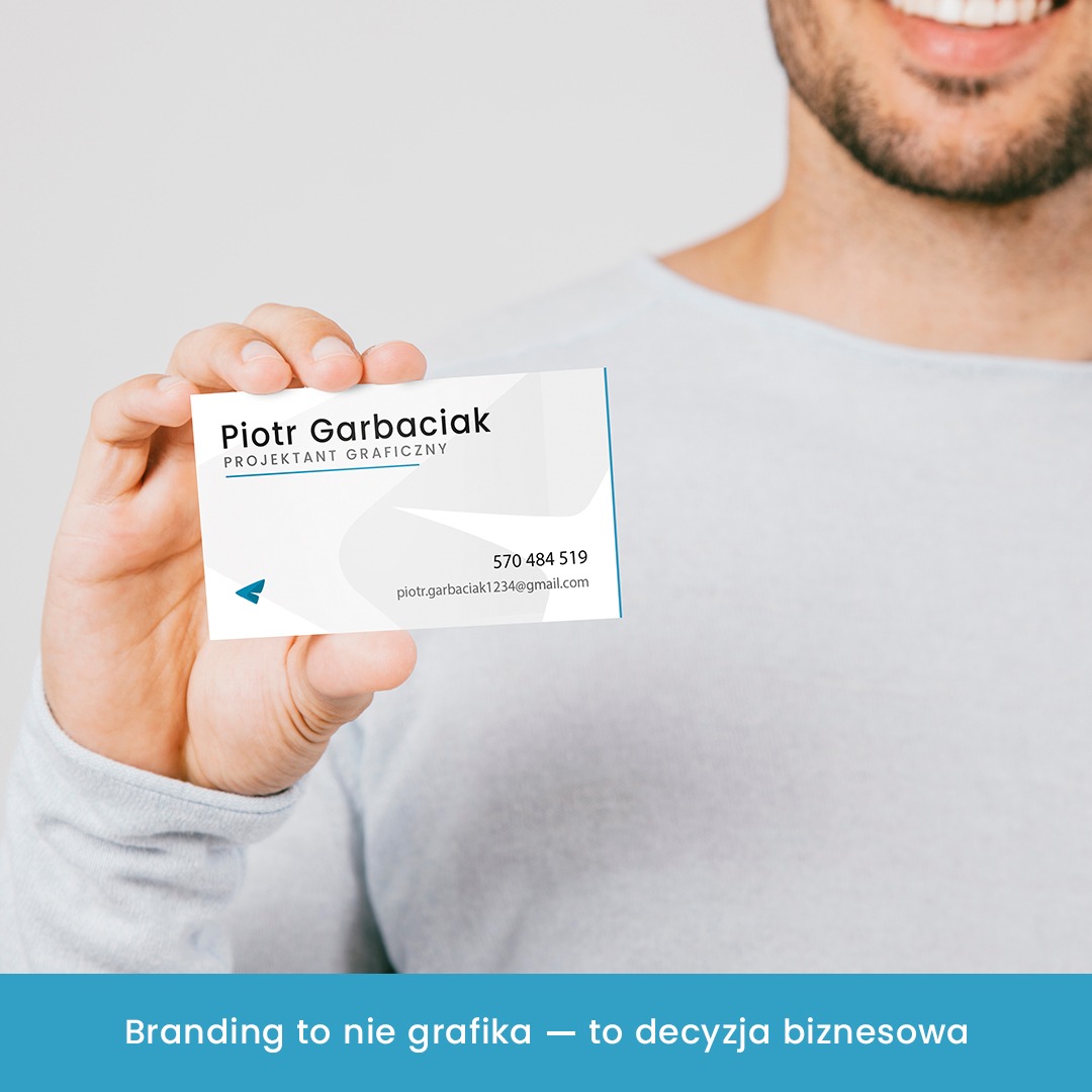 Mężczyzna prezentuje wizytówkę z danymi kontaktowymi projektanta graficznego Piotra Garbaciaka z Zagórowa. Minimalistyczny design z akcentem błękitu.