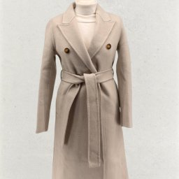 KM INVESTMENT POLAND PATRYK MIŁOSZ - Beżowy, wełniany płaszcz damski z paskiem, zapinany na dwa guziki, prezentowany na manekinie na tle jasnej ściany. Elegancki krój, idealny na chłodniejsze dni.