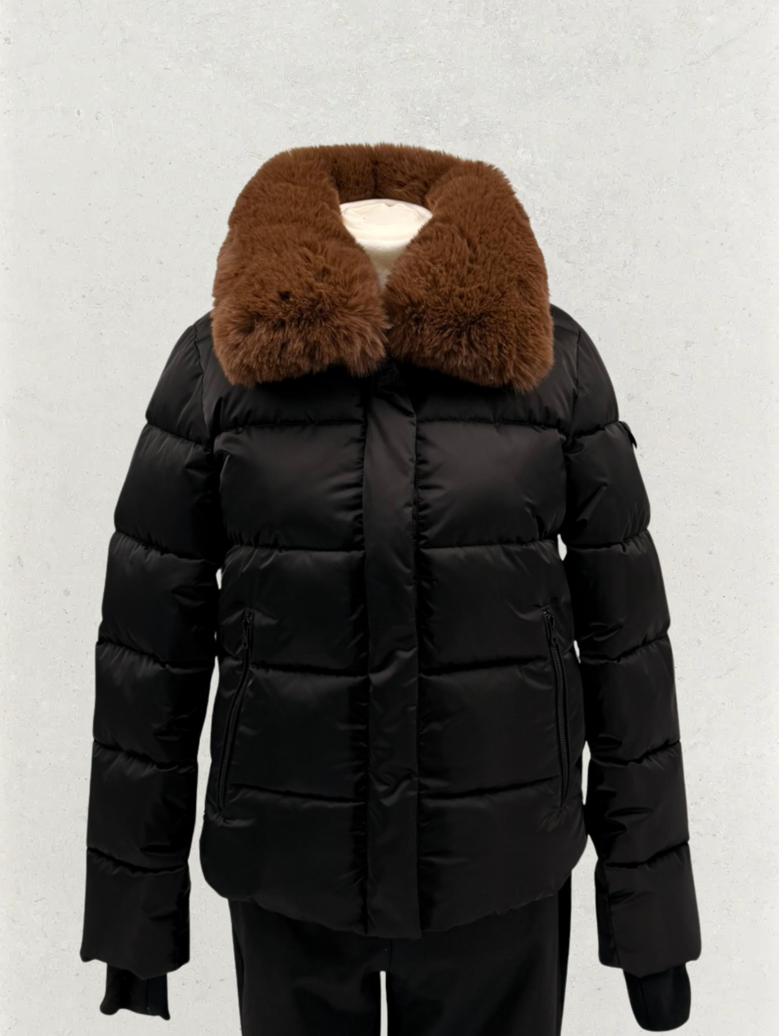 Czarna, pikowana kurtka z brązowym futrzanym kołnierzem, prezentowana na manekinie w Radomiu. Elegancki fason, idealny na chłodniejsze dni. Detal: widoczne kieszenie.