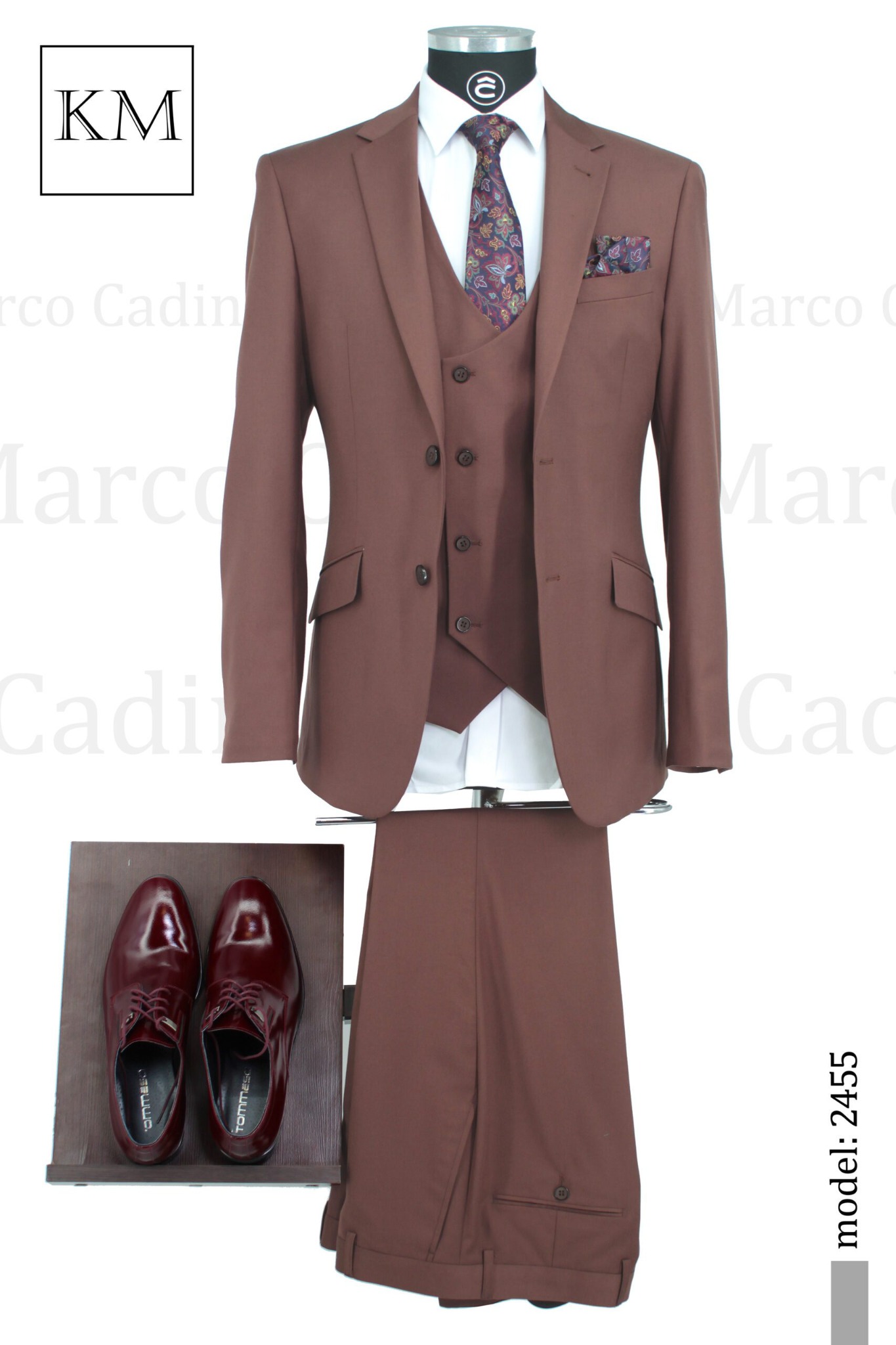 Brązowy, trzyczęściowy garnitur męski z wzorzystym krawatem i poszetką, uzupełniony o lakierowane, bordowe buty. Model 2455.
