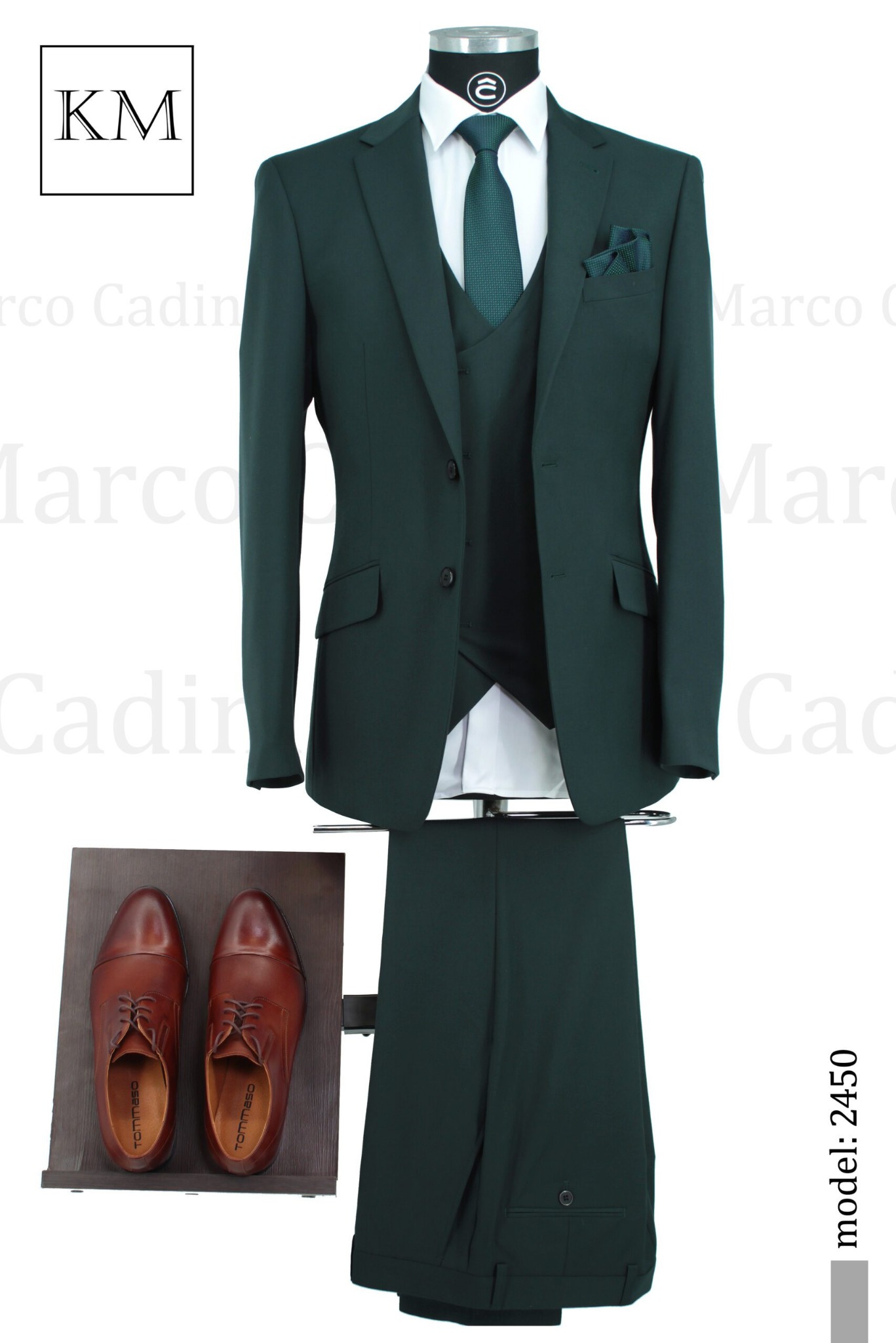 Elegancki, ciemnozielony garnitur trzyczęściowy z brązowymi skórzanymi butami. Model 2450. Widoczne logo KM. Całość na białym tle.