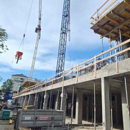 FIRMA OGÓLNOBUDOWLANA ANDRZEJ KIELIAN - Budowa budynku żelbetowego w toku: widoczne szalunki, zbrojenia, betonowe słupy, dźwigi i betoniarka. Etap wznoszenia konstrukcji, praca wre.