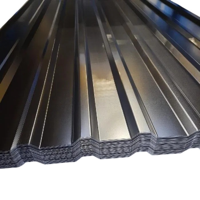 Stos arkuszy blachy trapezowej w kolorze grafitowym, ułożonych jeden na drugim. Widoczne profilowania i krawędzie arkuszy. Metaliczny połysk powierzchni.