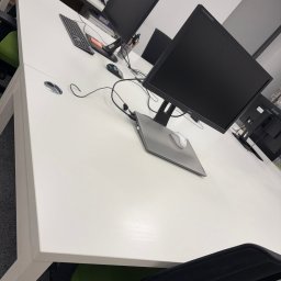GlowClean Kinga Opach - Białe biurko w biurze z komputerem, klawiaturą i myszką. Widok z góry na uporządkowane stanowisko pracy. Czyste blaty, ergonomiczne krzesło.