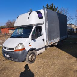 Usługi Transportowe RALF-PORT RAFAŁ CZOIK - Biały samochód dostawczy Renault Master z plandeką na podwórku, cień osoby w kadrze. Błękitne niebo w tle.