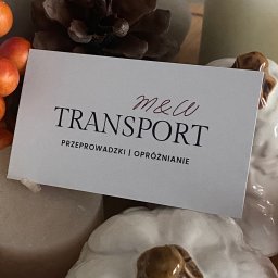 M&W Transport - Wizytówka firmy transportowej 'M&W Transport' z ofertą przeprowadzek i opróżniania mieszkań, umieszczona na dekoracyjnym tle z dyni i szyszki.