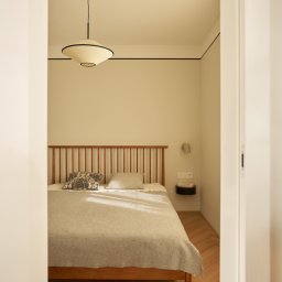 Anna Komorowicz Studio - Sypialnia w stylu retro z drewnianym łóżkiem, lampą wiszącą i parkietem w jodełkę. Minimalistyczny wystrój z akcentami vintage i ciepłym oświetleniem.